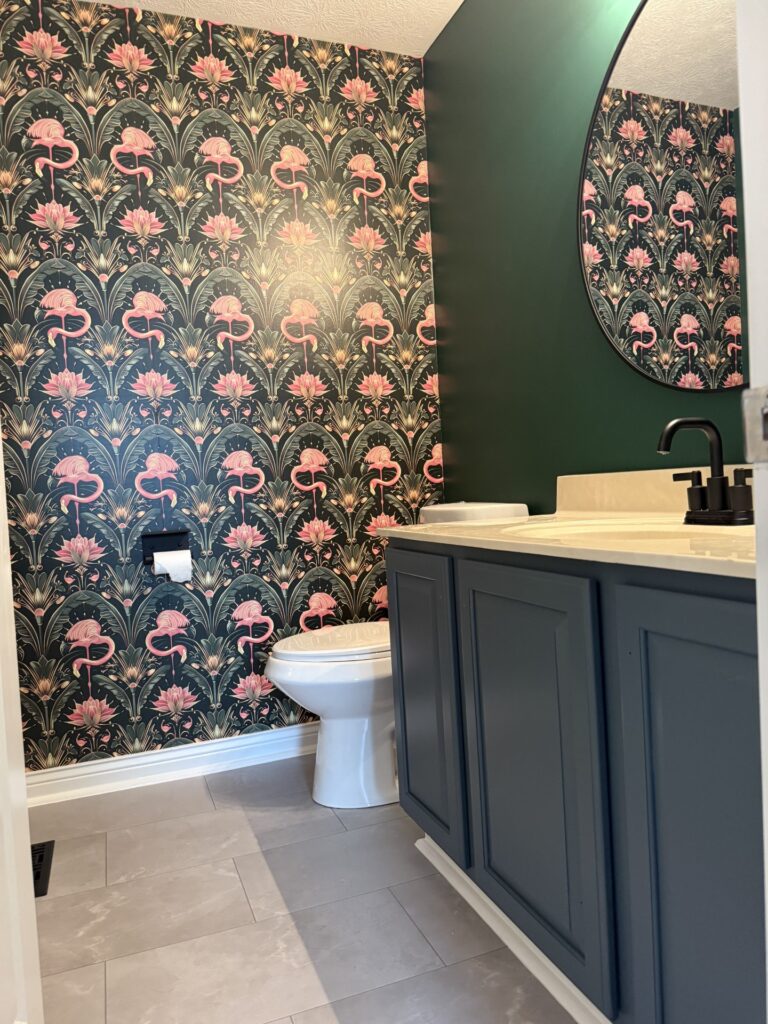 Pink flamingo art deco wallpaper in a powder room with a dark green painted wall